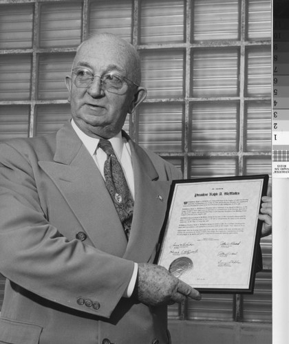 Photograph of Ralph A. McMullen holding his 10th anniversary citation