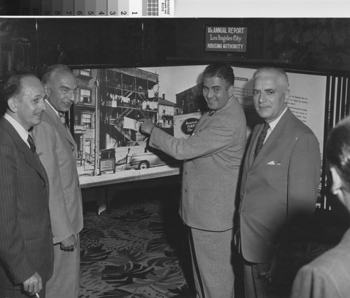 Photograph of municipal officials posing in front of exhibit for 10th Annual Report of the Los Angeles City Housing Authority