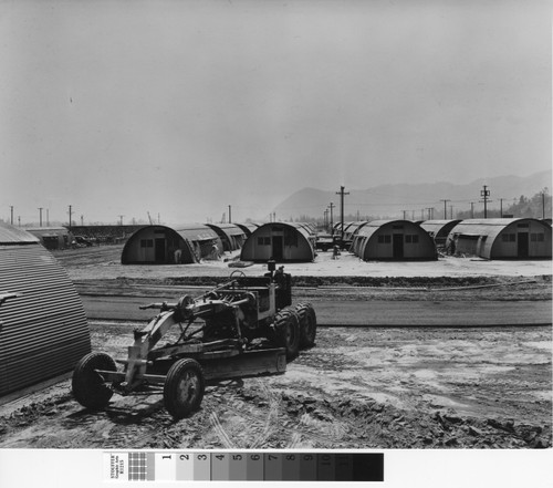 Photograph of Quonset hut with road scraper in foreground