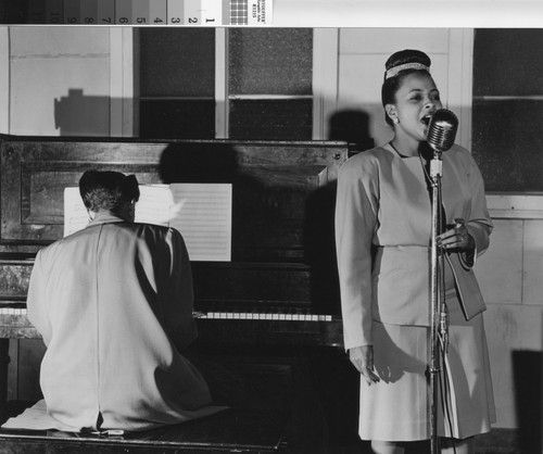 Photograph of a woman singing while another plays a piano at Corregidor Park