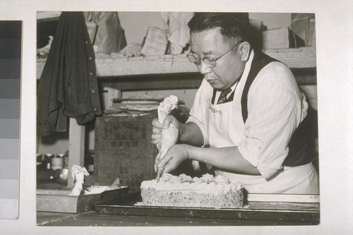 [Fong Fong Hoo, owner of ice cream parlor, decorating cake. Cf. No. 26.]