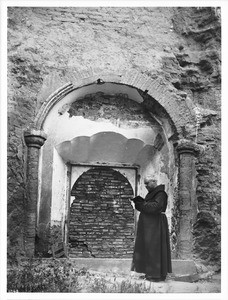 Father Superior O'Keefe standing at a walled-up doorway of Mission San Luis Rey de Francia, California, 1904