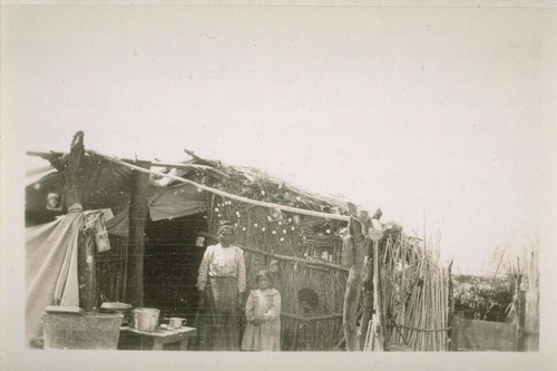 A prosperous appearing family domiciled in Mexicali almost on the line. Her teeth were filled with much gold. On her stove were tortillas cooking and on the ends of the reeds which formed the wells of the residence were empty egg shells. She smilingly consented to have her picture taken while her husband was taking a siesta within