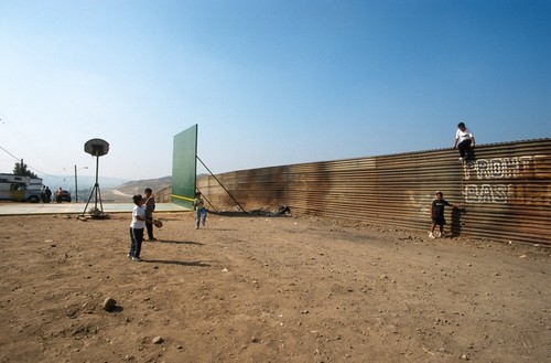 The Rules of the Game: ball court and border fence with children playing