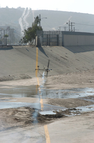 Aerial Bridge: toy helicopter flying over yellow U.S. - Mexico border demarcation line