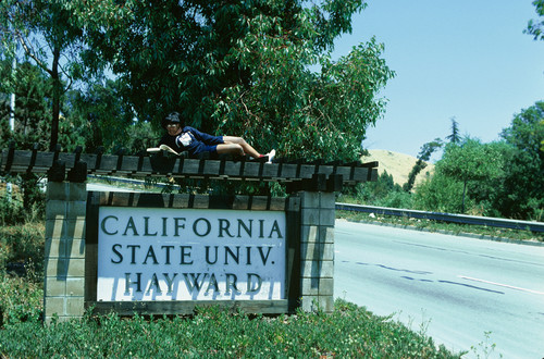 Slide of sign on Hayward Hills campus: "California State Univ. Hayward" with person lying on top of sign reading