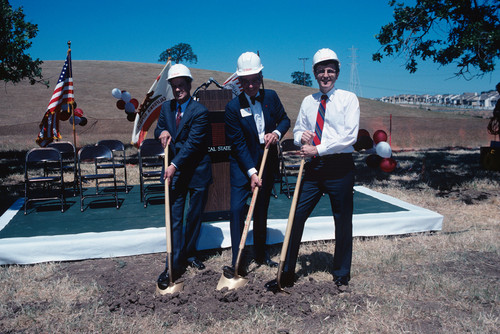 Three men posing for a ceremonial groundbreaking with shovels