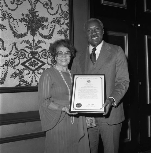 Ruth Washington and Nate Holden posing with a plaque at the Brotherhood Crusade dinner, Los Angeles, 1978