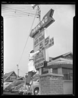 Elias Mushro adjusting price signage at National Auto Park lot, 1621 N. Hudson Avenue in Hollywood, Calif., 1949