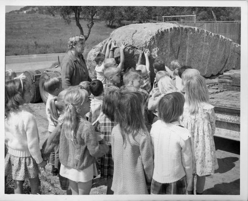 School children touching boulder used for the plaque of the Wakamatsu Tea and Silk Farm Colony historical landmark