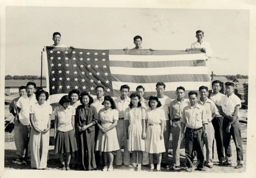 Internees holding American flag at Granda Relocation Center