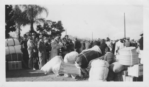 Japanese Americans pile luggage at train station preparing to leave for internment