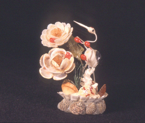 White crane and two large flower blossoms on pedestal made from shells