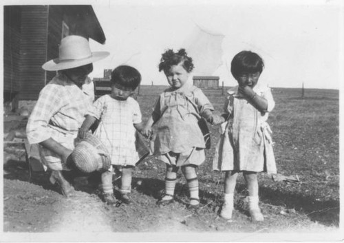 Unidentified children and woman outside on farm