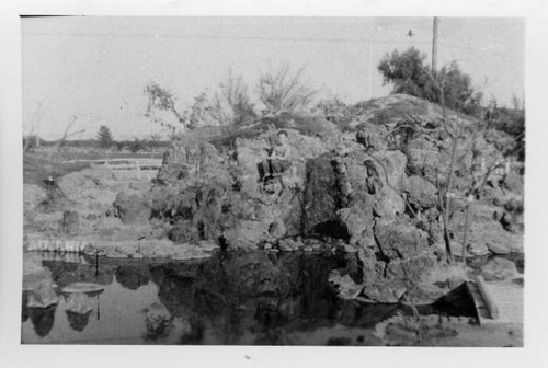 Boy sitting on rock in Japanese garden at Poston Relocation Center