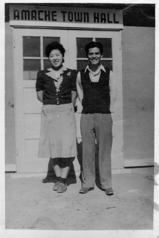 Harry and Ruth Tsuruda standing in front of Amache Town Hall at Granada Relocation Center