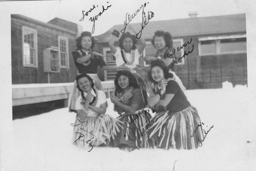 Women wearing grass skirts outside barracks at Tule Lake Relocation Center