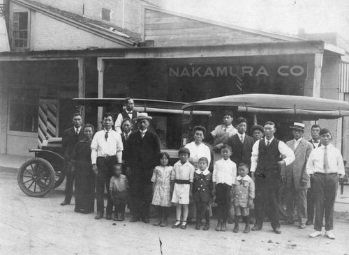 Japanese Americans in front of the Nakamura Company building with two delivery trucks