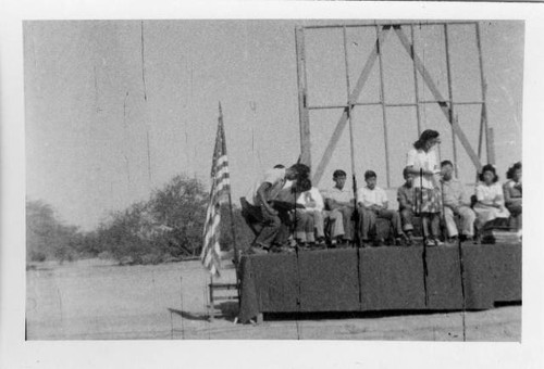 Woman on stage during ceremony at Poston II school [?]