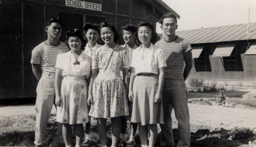 Seven young adults outside Poston II Relocation Center school offices