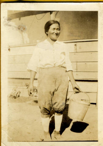 Misao Nakano carrying pail on family farm in Yolo County