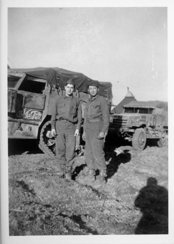 Tom Mizuno (right) with another soldier standing in front of army trucks