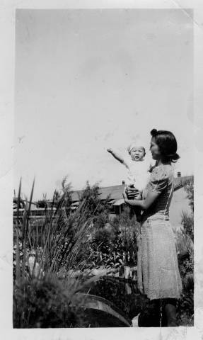 Mildred Yaeko Nakano holding son, Alan Takeji Nakano in Japanese garden at Granada Relocation Center