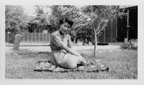 Woman sitting on lawn outside Poston Relocation Center school