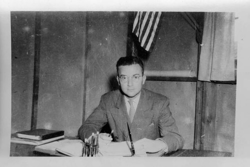 Dallas McLaren at desk in school barrack building at Poston II Relocation Center