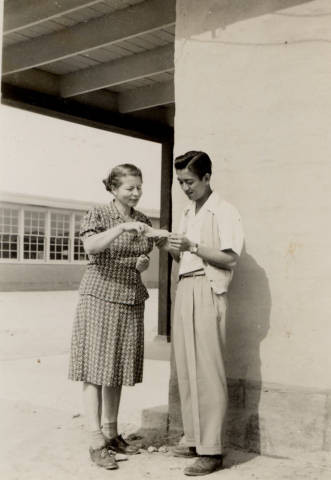 Kazuo George Ikeda and woman outside school building at Poston II Relocation Center