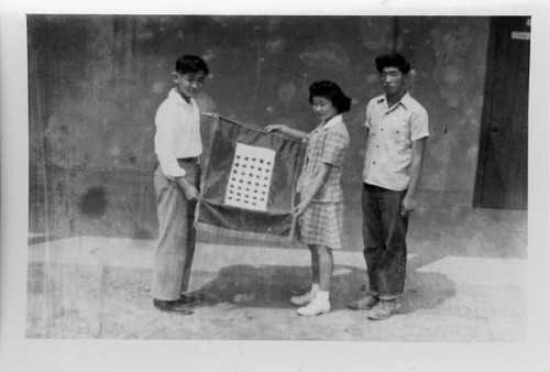 Students of Poston Relocation Center school holding military service banner