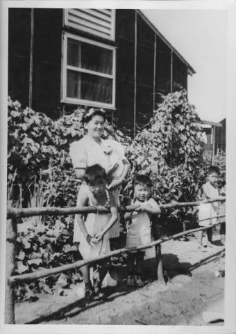 Woman and children standing alongside barracks Jerome Relocation Center