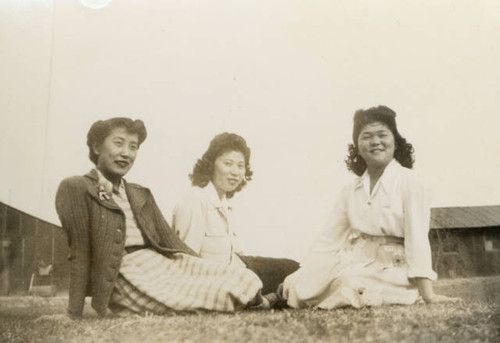 Three women sitting on grass at Poston II Relocation Center