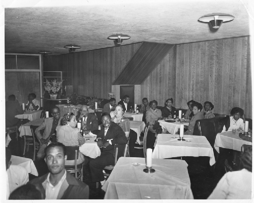 Male and female patrons seated at white cloth covered tables, Slim Jenkins nightclub Oakland, California