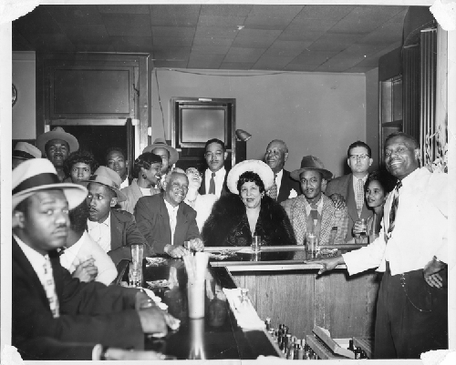 Group photograph of patrons seated around bar at Slim Jenkins Bar and Restaurant Oakland, California