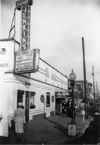Pedestrians walking on sidewalk in front of Slim Jenkins Bar and Restaurant Oakland, California