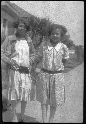 Two young women standing on sidewalk