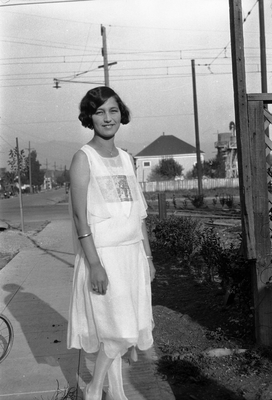 Young woman in sleeveless dress standing on sidewalk