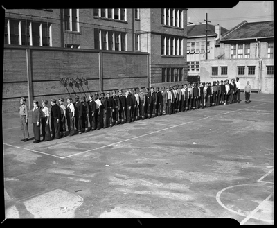 Boys standing in a line next to Prescott School building