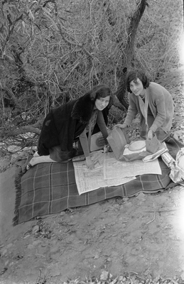 Two women setting up picnic on blanket