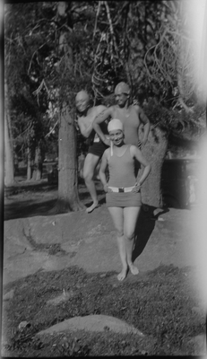 Three young women in swim suits and caps standing on rock