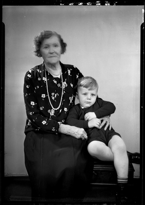 Portrait of boy and woman in floral patterned dress sitting on bench