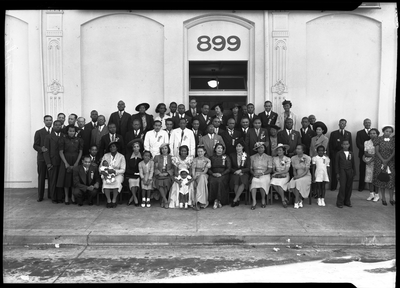 Group photograph of men and women in front building