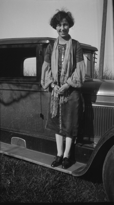 Young woman standing on running board of automobile