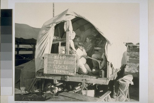 Both these families are now forced to live and eat and sleep in and under the "covered wagon" truck at the right, because the other truck is used as a "pest house" for two members of the family who are ill. "Our friends back home write and ask us about jobs in the shipyards," they say. "We write back and tell em wages are high, but we wouldn't have come if we'd known we couldn't find houses to live in."