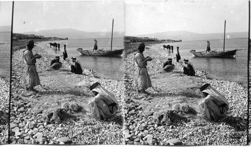 Fishermen mending nets at Jordan’s entrance to Sea of Galilee. Palestine