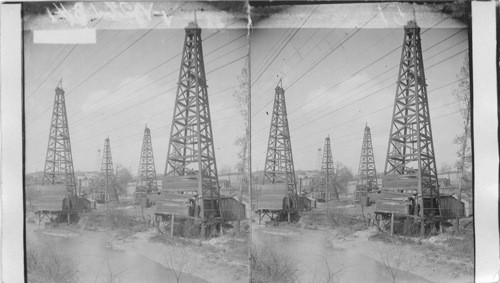 A cluster of oil wells along side a creek. Penna