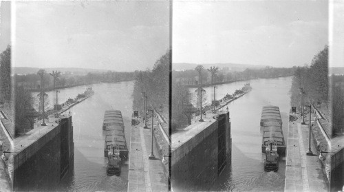 Boat and barges leaving the lock going down the river with boat and barges of oil waiting to enter the lock. ? Tennessee, Georgia, Alabama