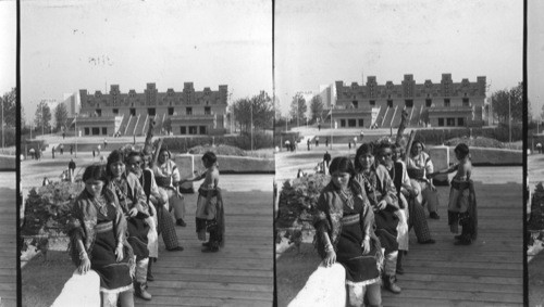 Indians from four tribes live peacefully in the Indian village. This view is from the balcony of the Hopi House, and shows several Hopis in full costume. The Maya Temple is shown in the background