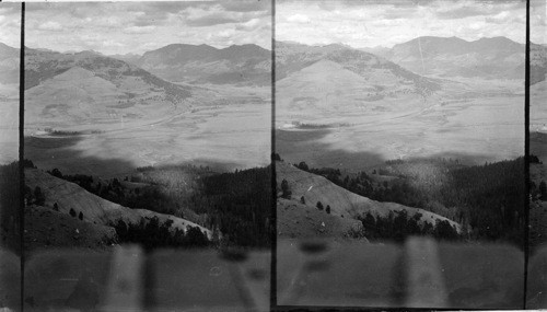 Looking N.E. into the valley of the Lamar River from the face of Specimen Ridge near the lower edge of the Fossil Forest, Yellowstone National Park, Wyo. In the distance the valley of Soda Butte Creek open to the left, with the saddle back ridge of the Thunderer (elev. 10,300ft.) beyond it. On the extensive meadows in the river valley hundreds of tons of hay are cut and stacked during the late summer by the men employed at the Buffalo Ranch, which lies a few miles to out left. During the winter, this hay is fed to the herd of about 900 head of buffalo living in the Park, when the deep snows prevent them from finding pasturage on the remote mountain slopes and among the ravines which they frequent in summer. (Lat. 45N.; Long 110W.)